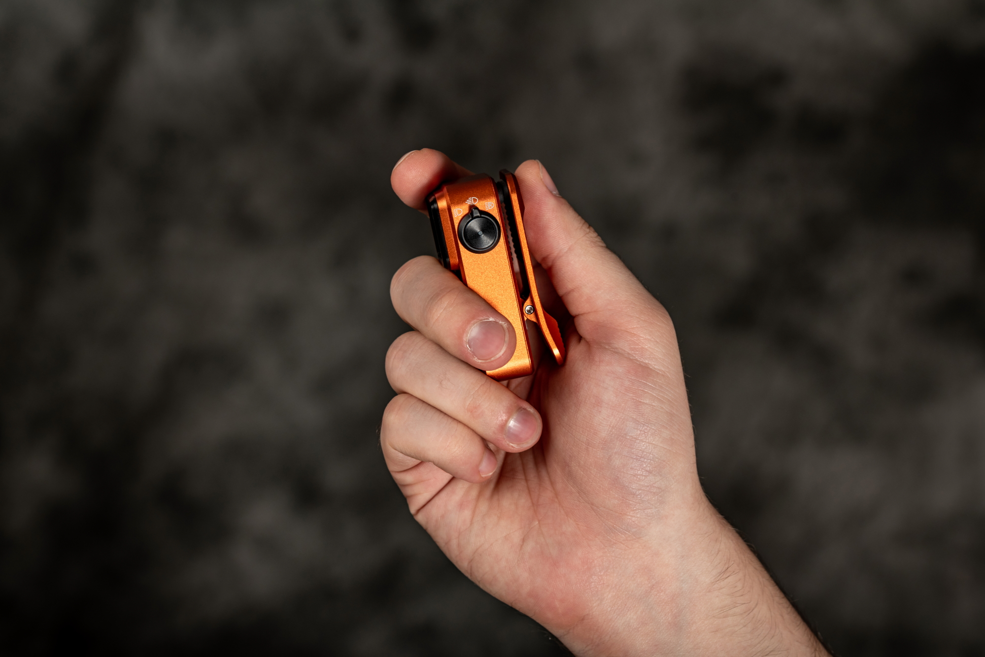 手に持ったオレンジ色の小型LED懐中電灯。