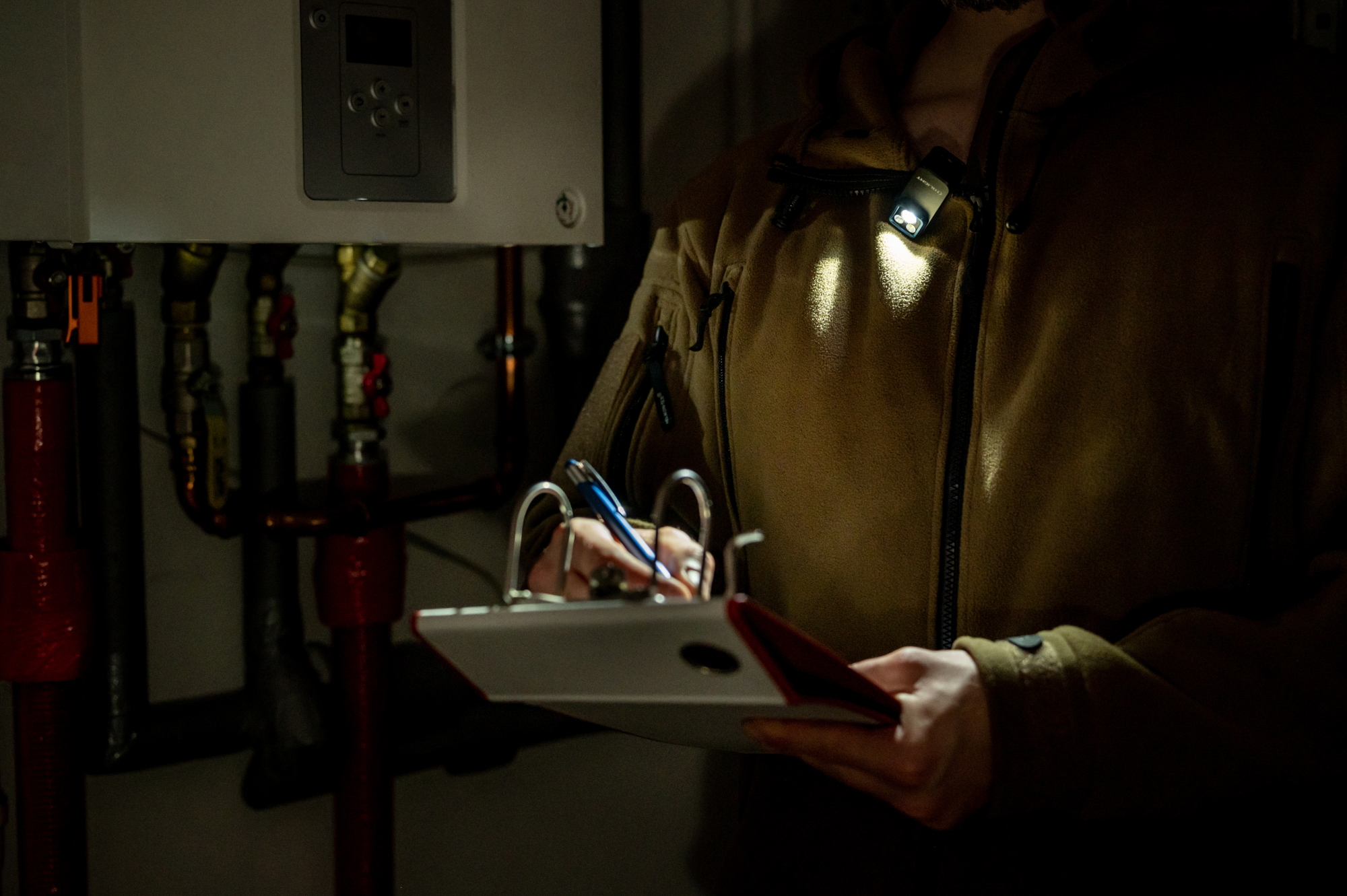 HVAC technician with clip-on light inspecting a boiler