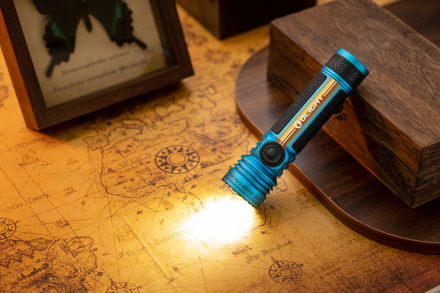 古地図を照らす青いOlight Seeker 4 Pro懐中電灯。探検や冒険に最適なパワフルな光。