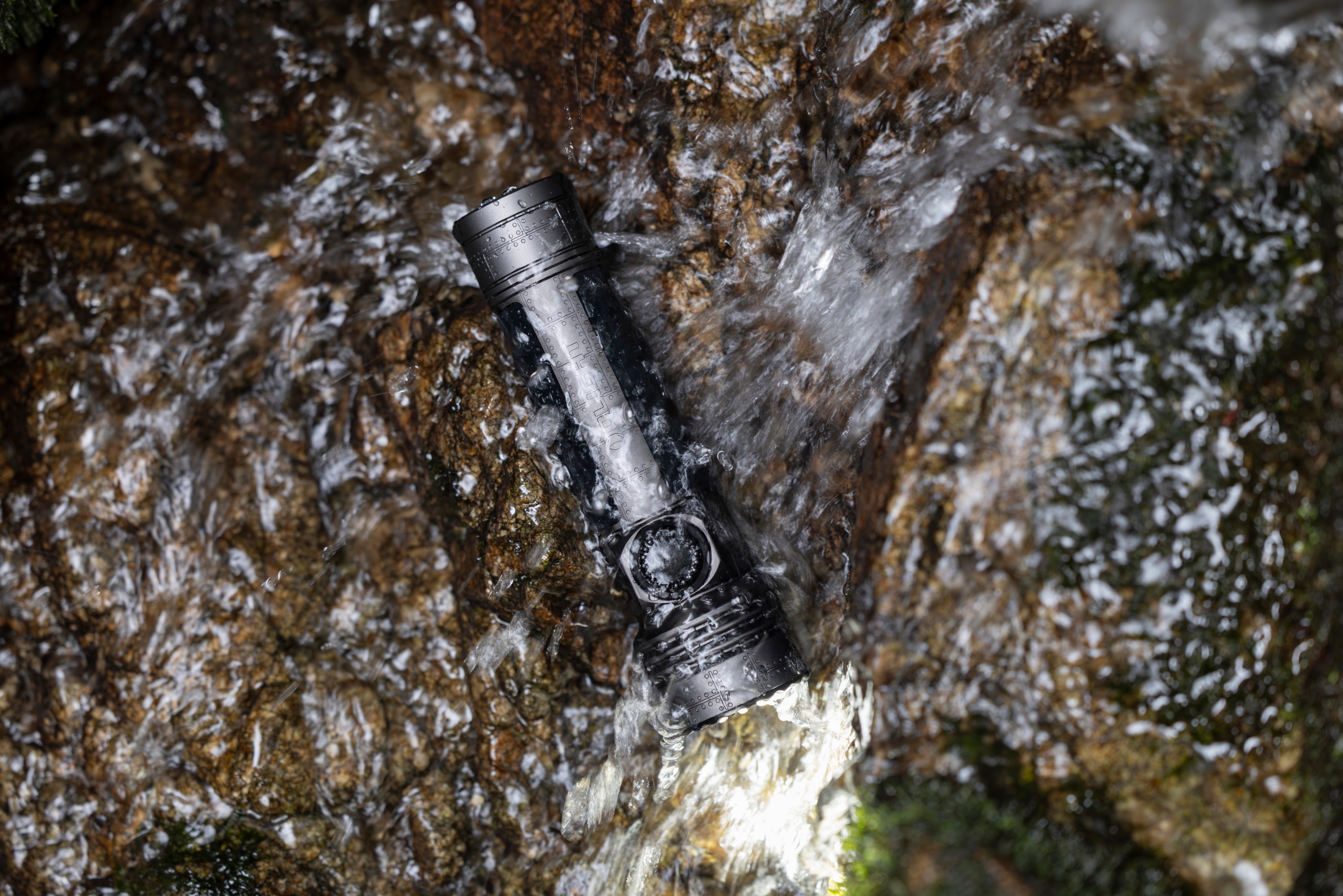 激しく流れる渓流の岩肌に置かれた、防水仕様の頑丈なタクティカル懐中電灯