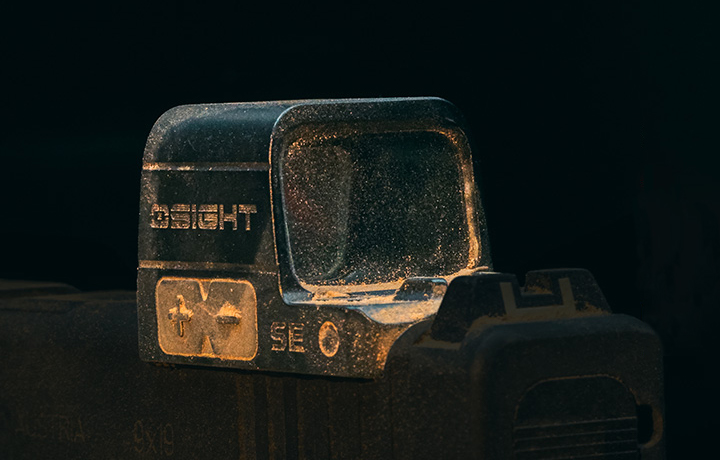 Optique point rouge OSIGHT poussiéreuse montée sur une arme à feu, soulignant son utilisation tactique et robuste.