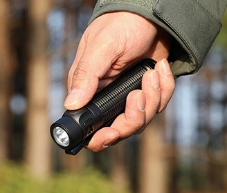 Kompakte schwarze LED-Taschenlampe in der Hand gehalten, ideal für Outdoor-Aktivitäten, Wandern und Camping im Wald.