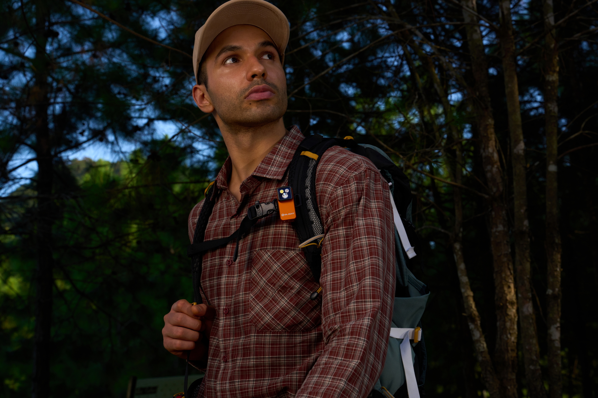 Hiker in forest with Olight clip-on safety light on pack strap