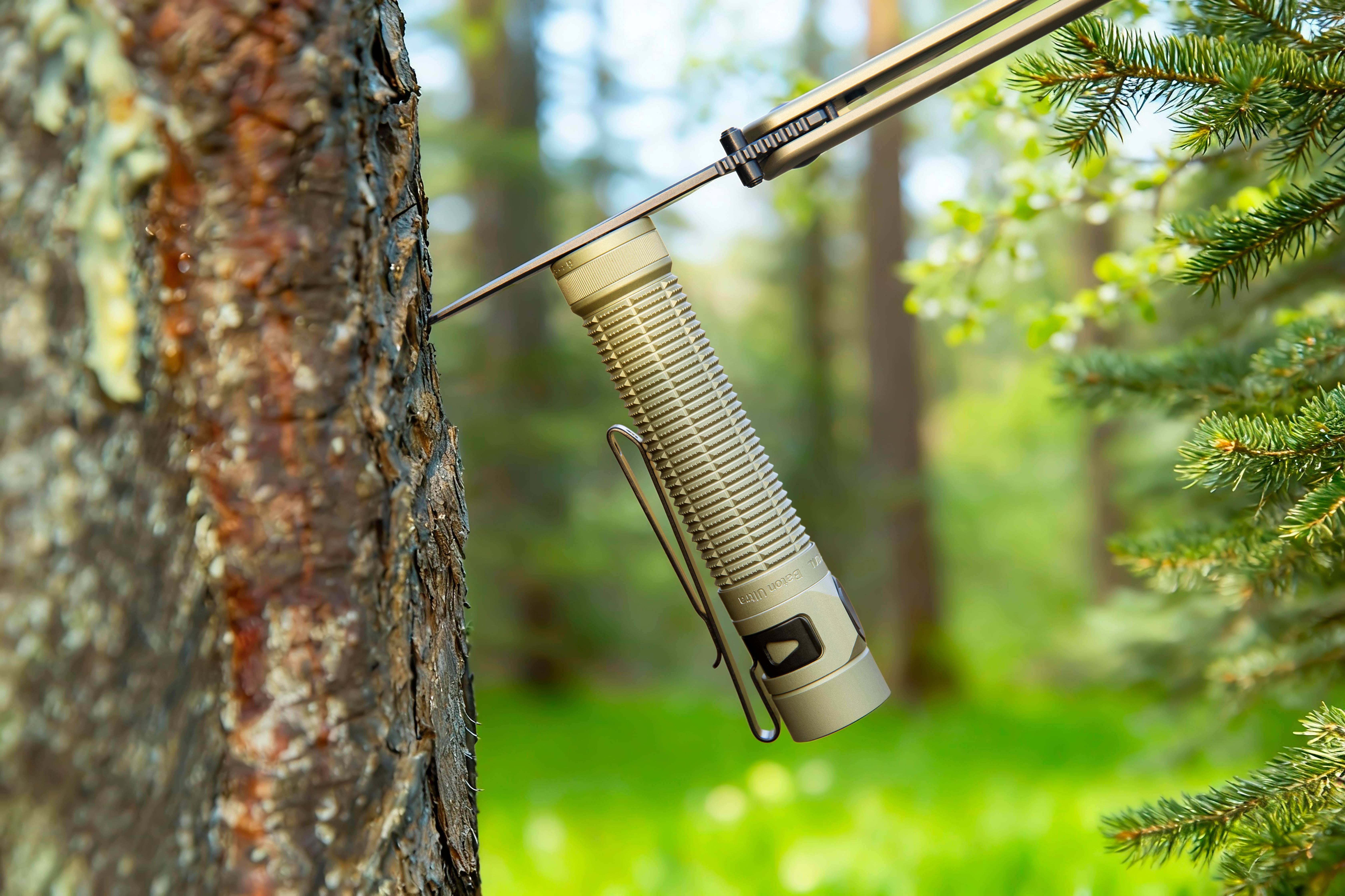 Linterna t&aacute;ctica compacta color arena adherida magn&eacute;ticamente a un cuchillo clavado en un &aacute;rbol. Equipo EDC de supervivencia para camping y aventuras al aire libre en el bosque.