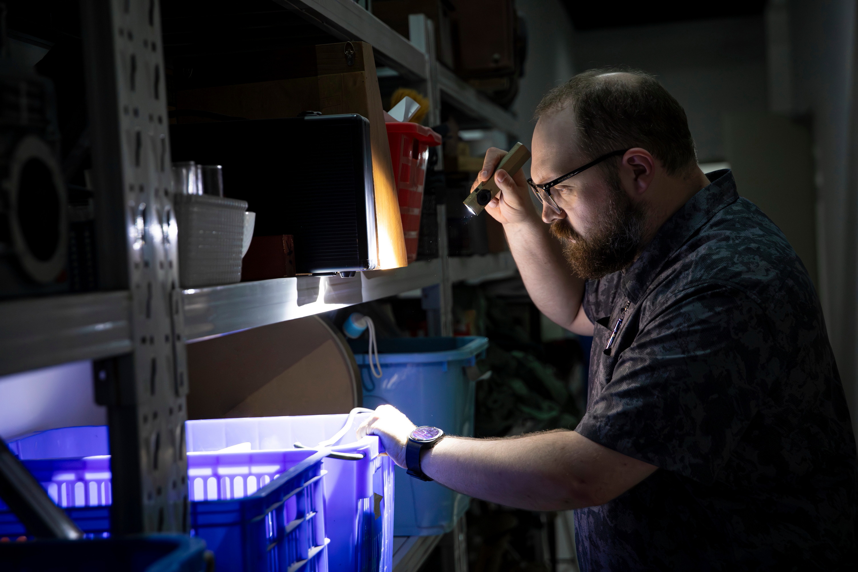 Professional home inspector using a high-quality flashlight in a dark crawl space