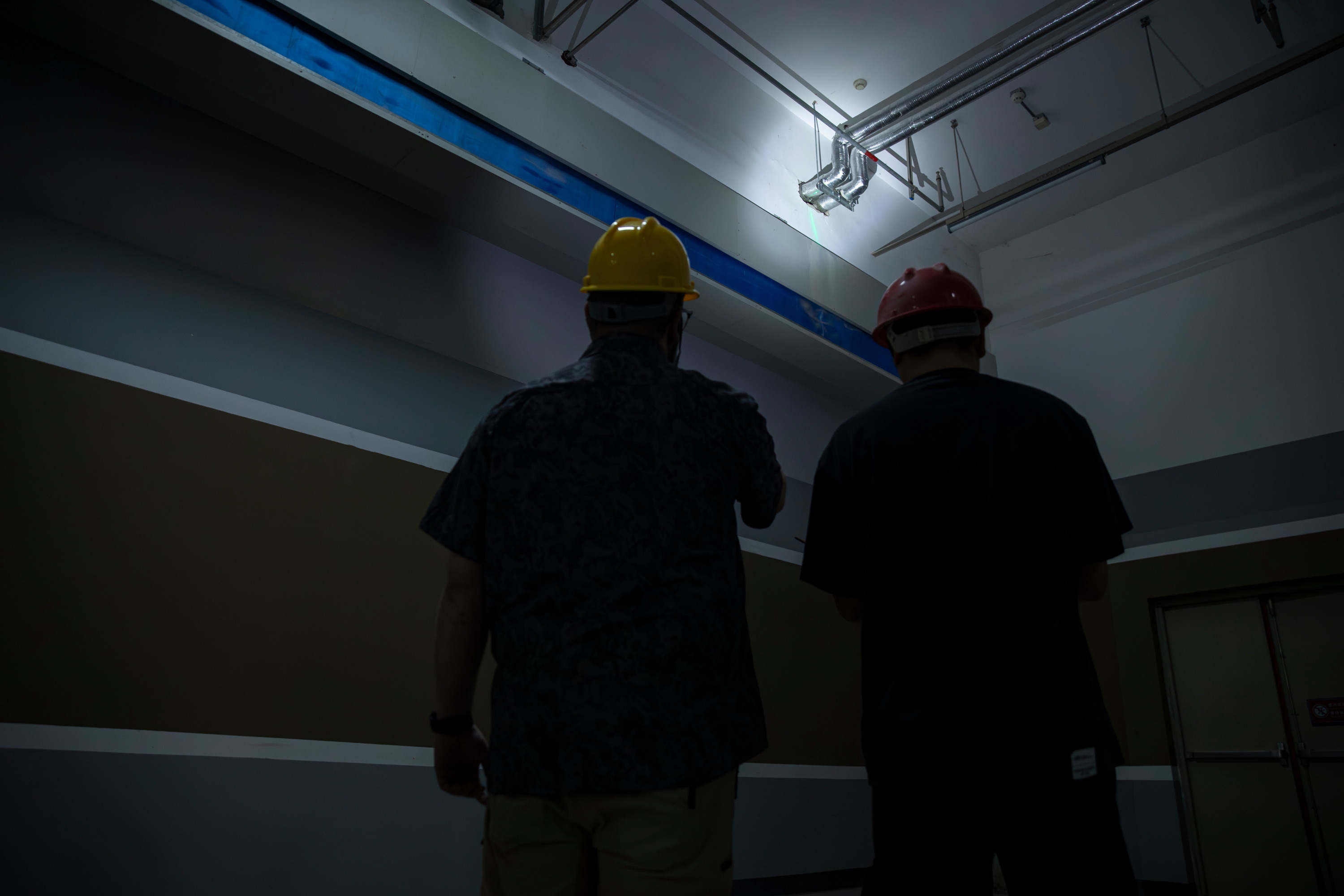 Engineers conducting a facility inspection of HVAC systems using a spotlight and laser pointer