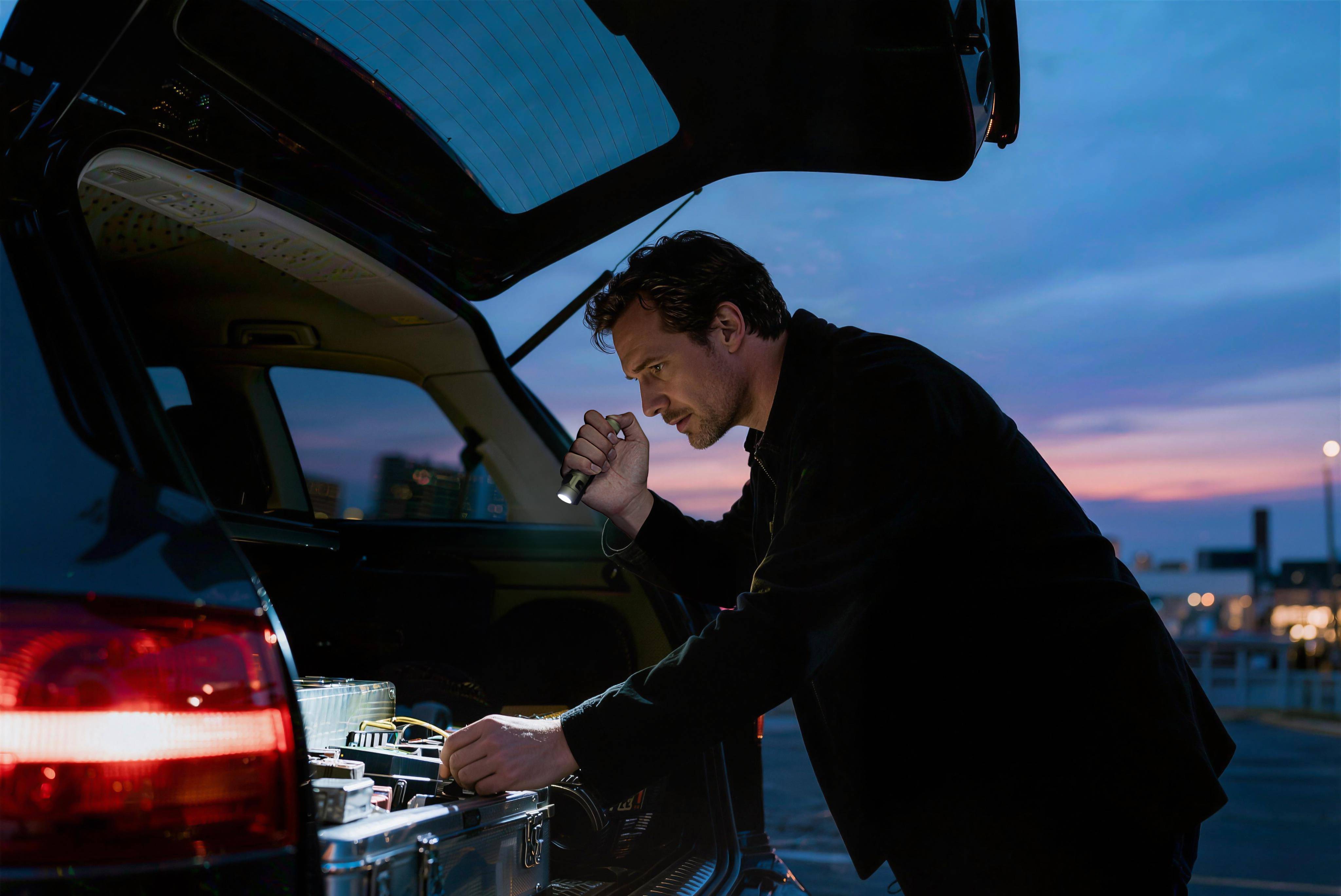 Man using a portable LED flashlight for emergency roadside assistance