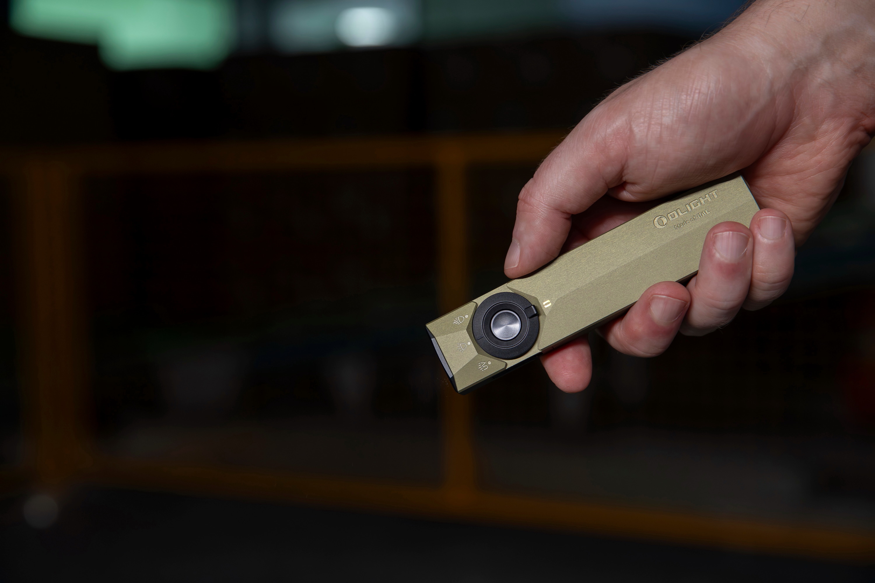 手でOlight Arkfeldフラット型懐中電灯を操作