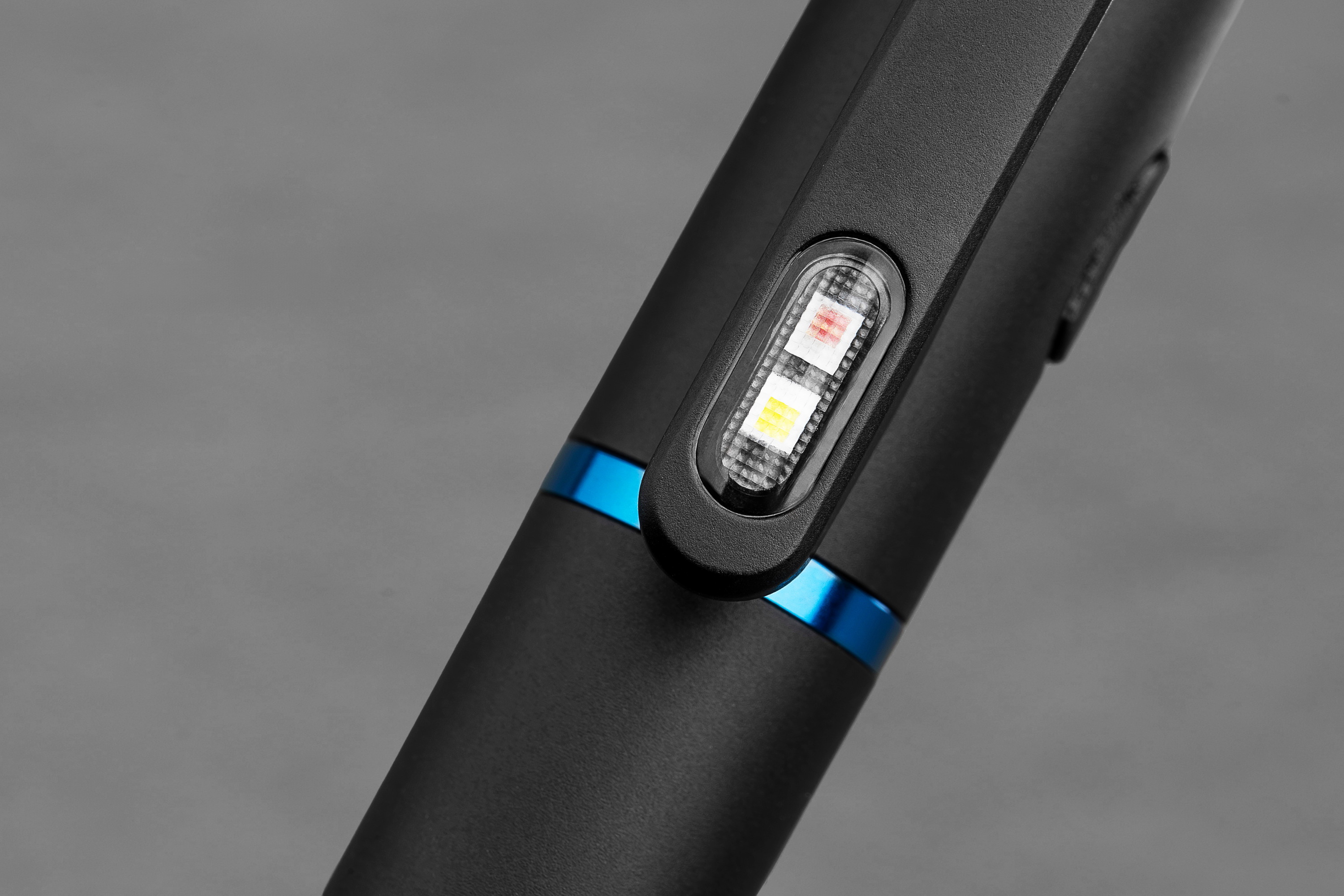 Close-up of a sleek black EDC flashlight or portable tool featuring dual LED indicators on a pocket clip and a blue metallic accent ring.