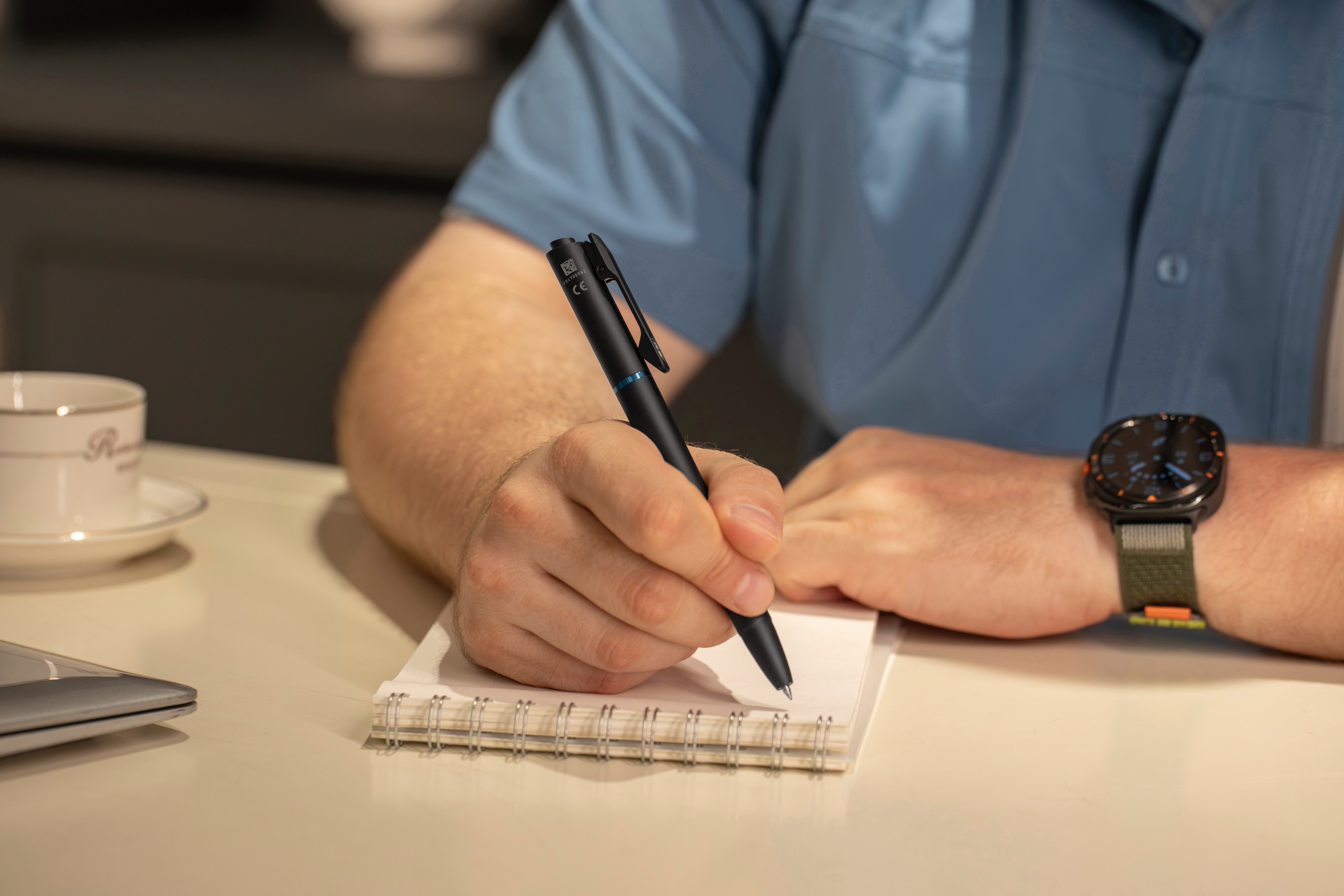 Official shot of a man writing in a notebook with an Olight pen.