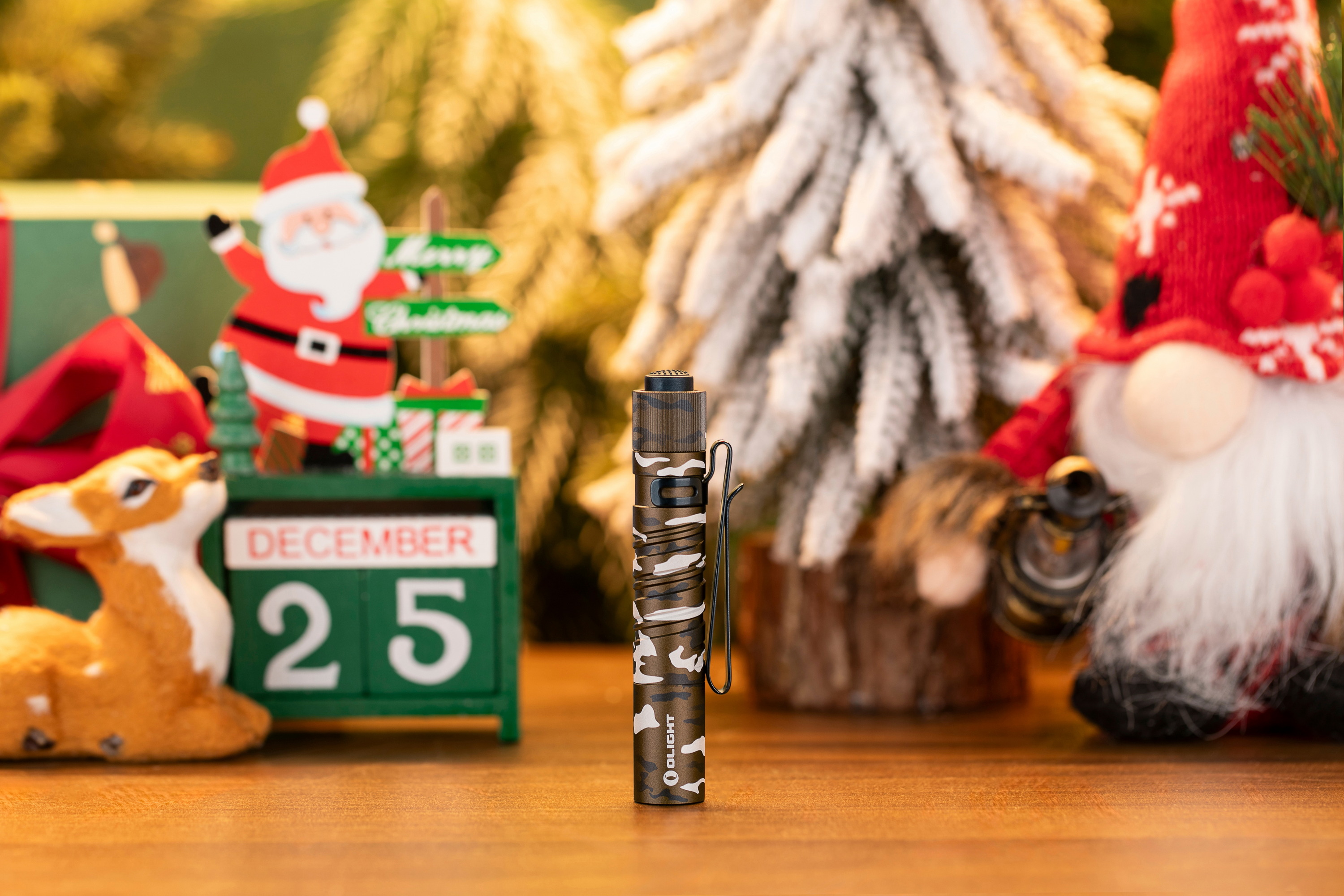 Olight camouflage flashlight on a wooden table.