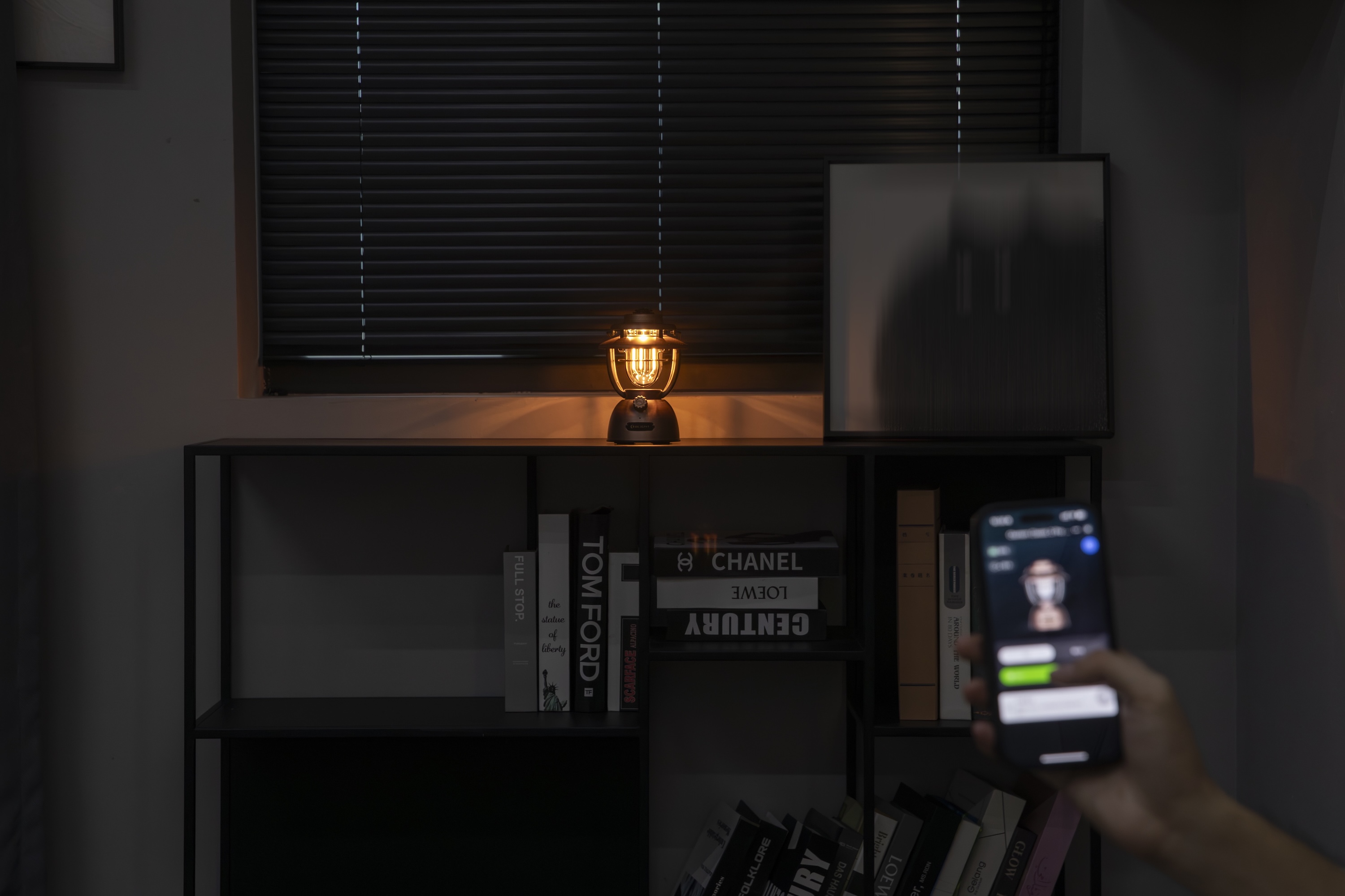 스마트폰 앱으로 제어되는 따뜻한 불빛의 빈티지 랜턴이 어두운 실내 책장 위 아늑한 분위기를 연출합니다.