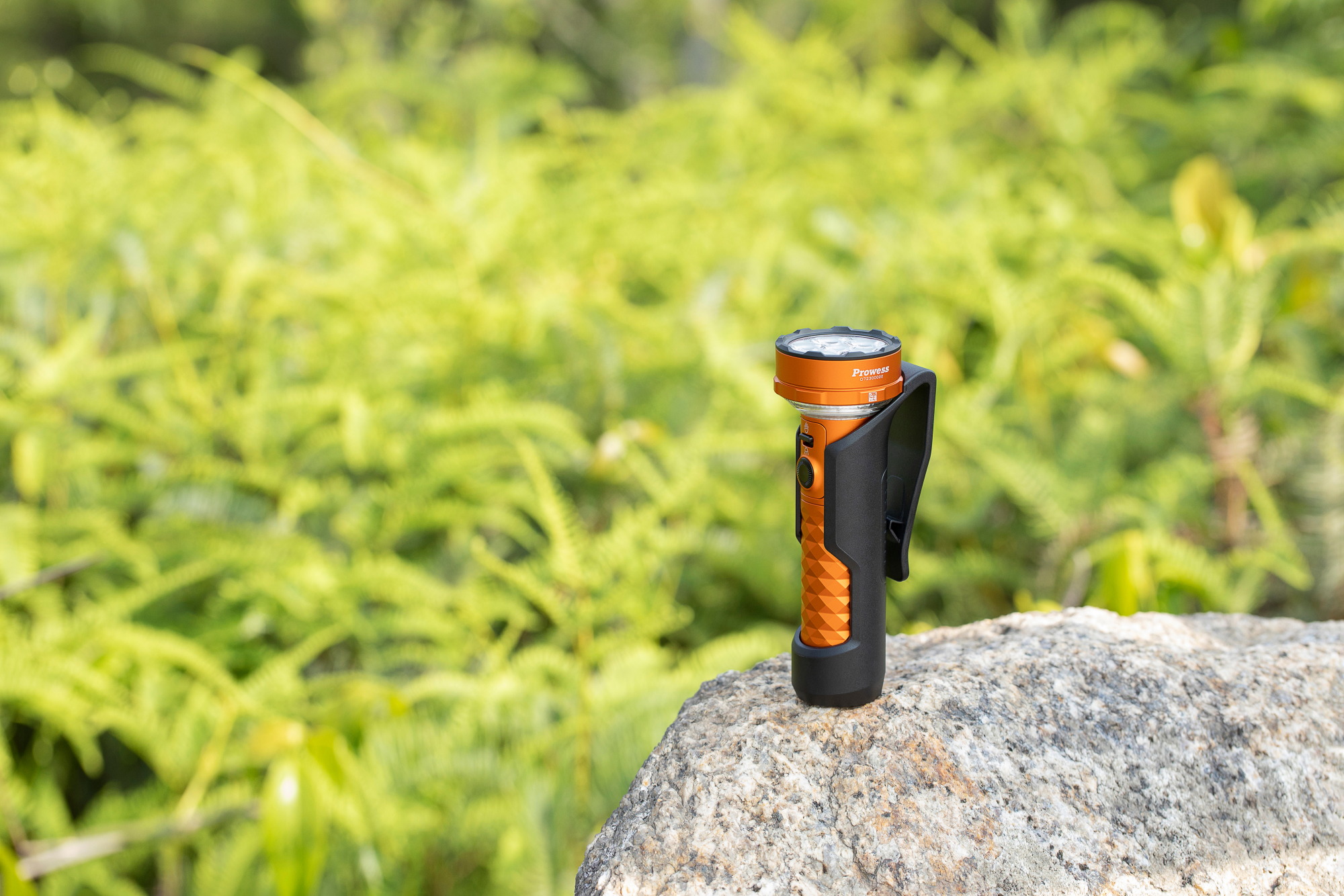 Linterna LED recargable Olight Prowess naranja con funda t&aacute;ctica sobre una roca al aire libre
