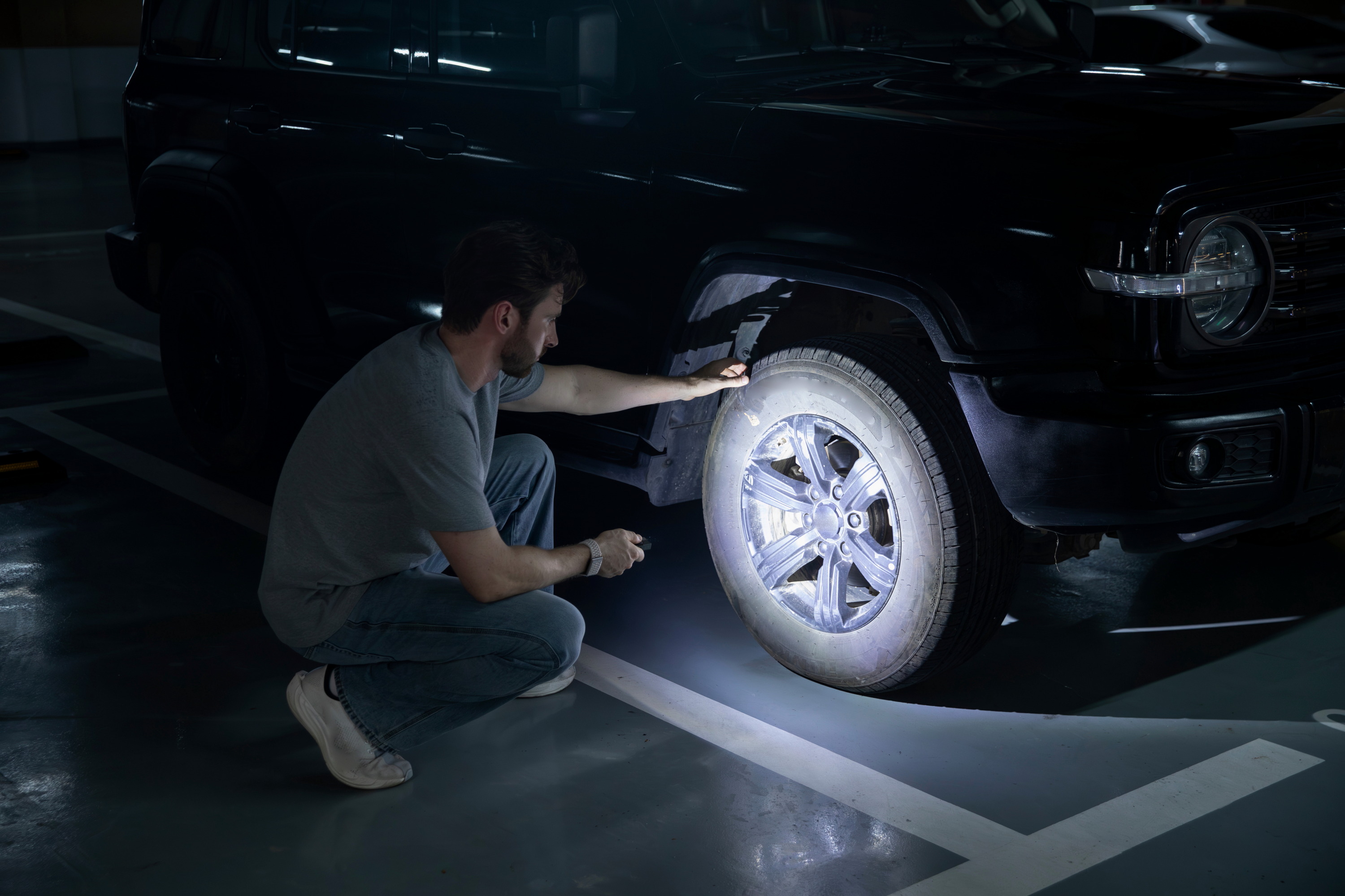 Inspecting a vehicle tire in a dark garage using the high-performance floodlight of the ArkPro series.