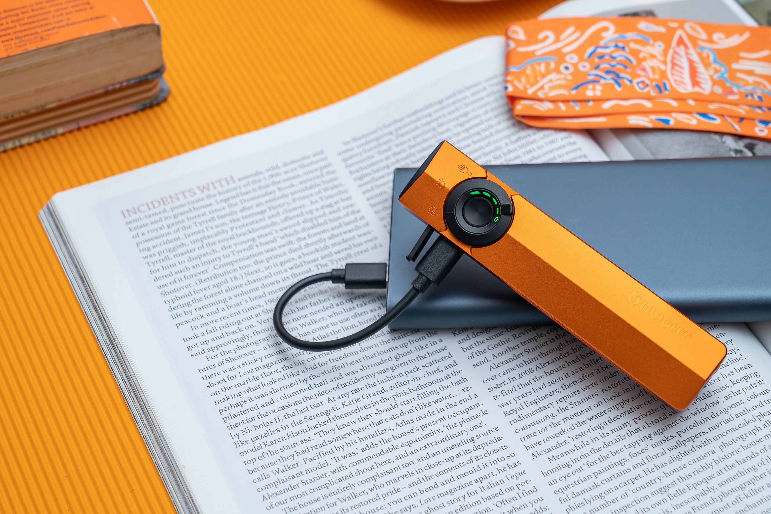 Orange Olight flashlight charging on an open book.