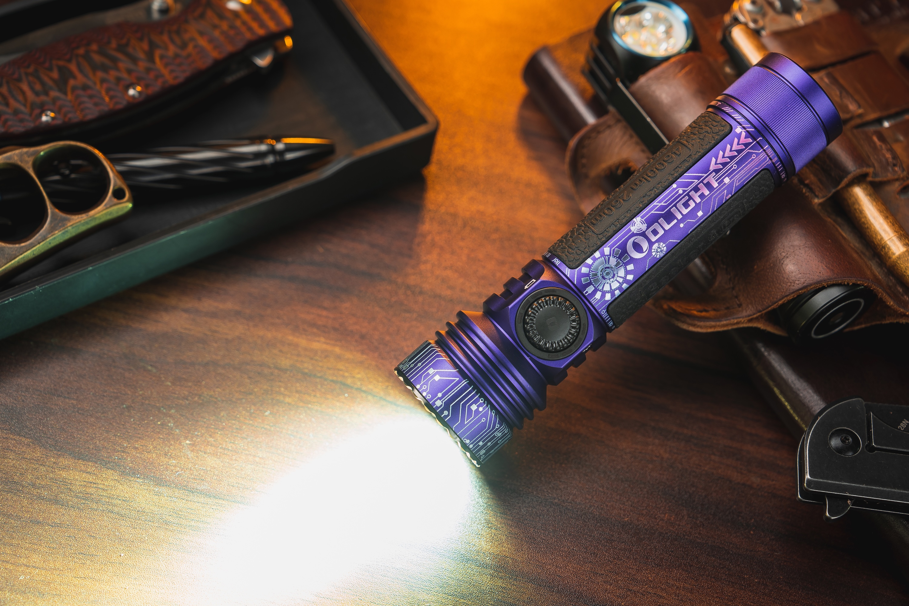 The Olight Seeker 4 Pro (4,600 lumens) paired with essential EDC gear including a multi-tool and pen on a wooden surface.