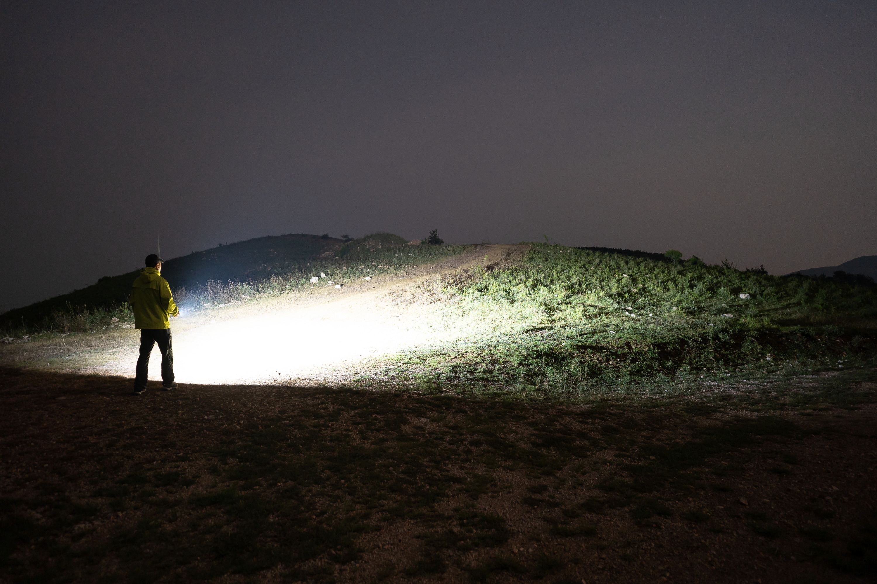 Hombre con chaqueta amarilla iluminando con linterna potente ArkPro