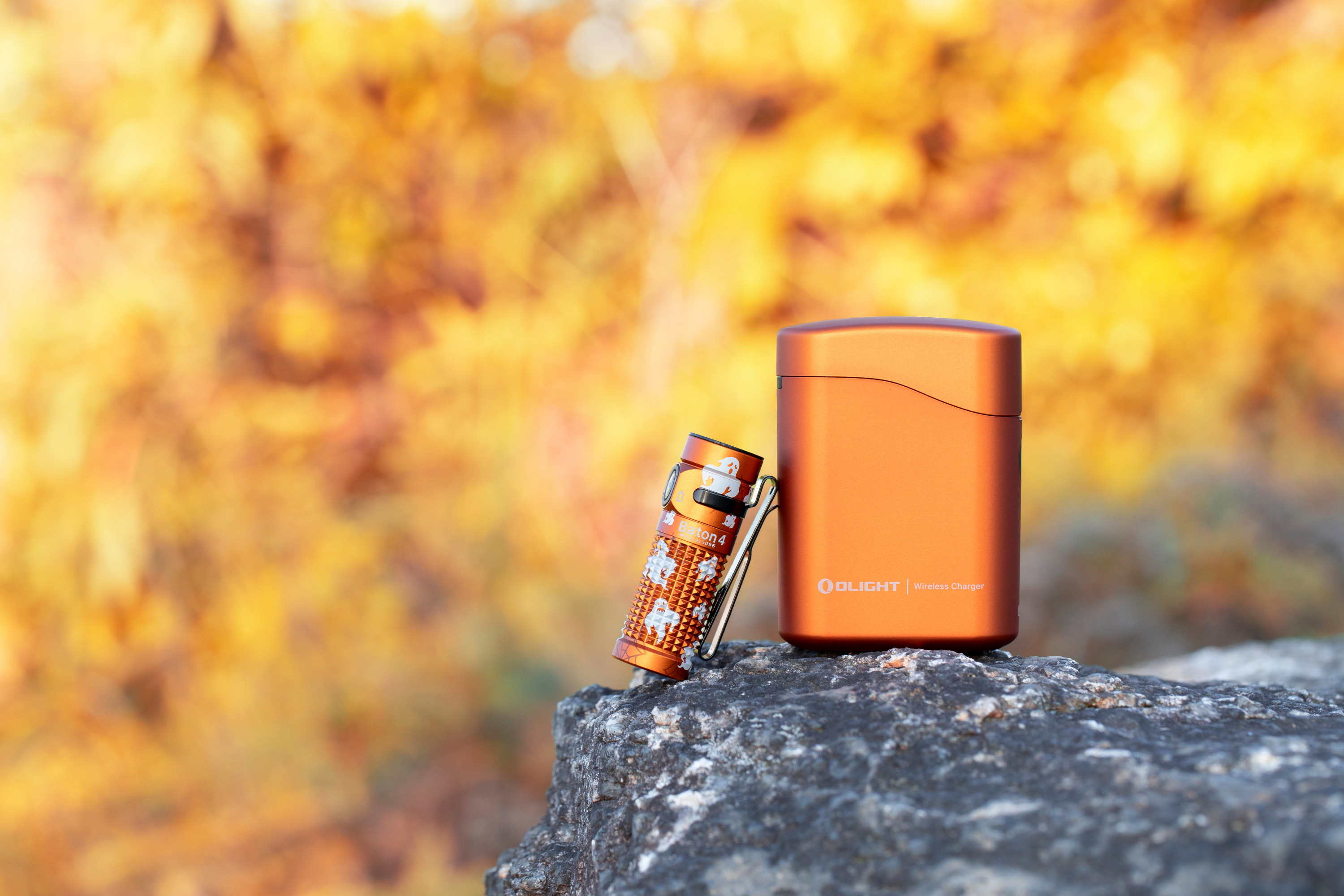 Lampe de poche Olight Baton 4 pos&eacute;e avec son bo&icirc;tier de charge en milieu naturel pour s&eacute;curiser la berge