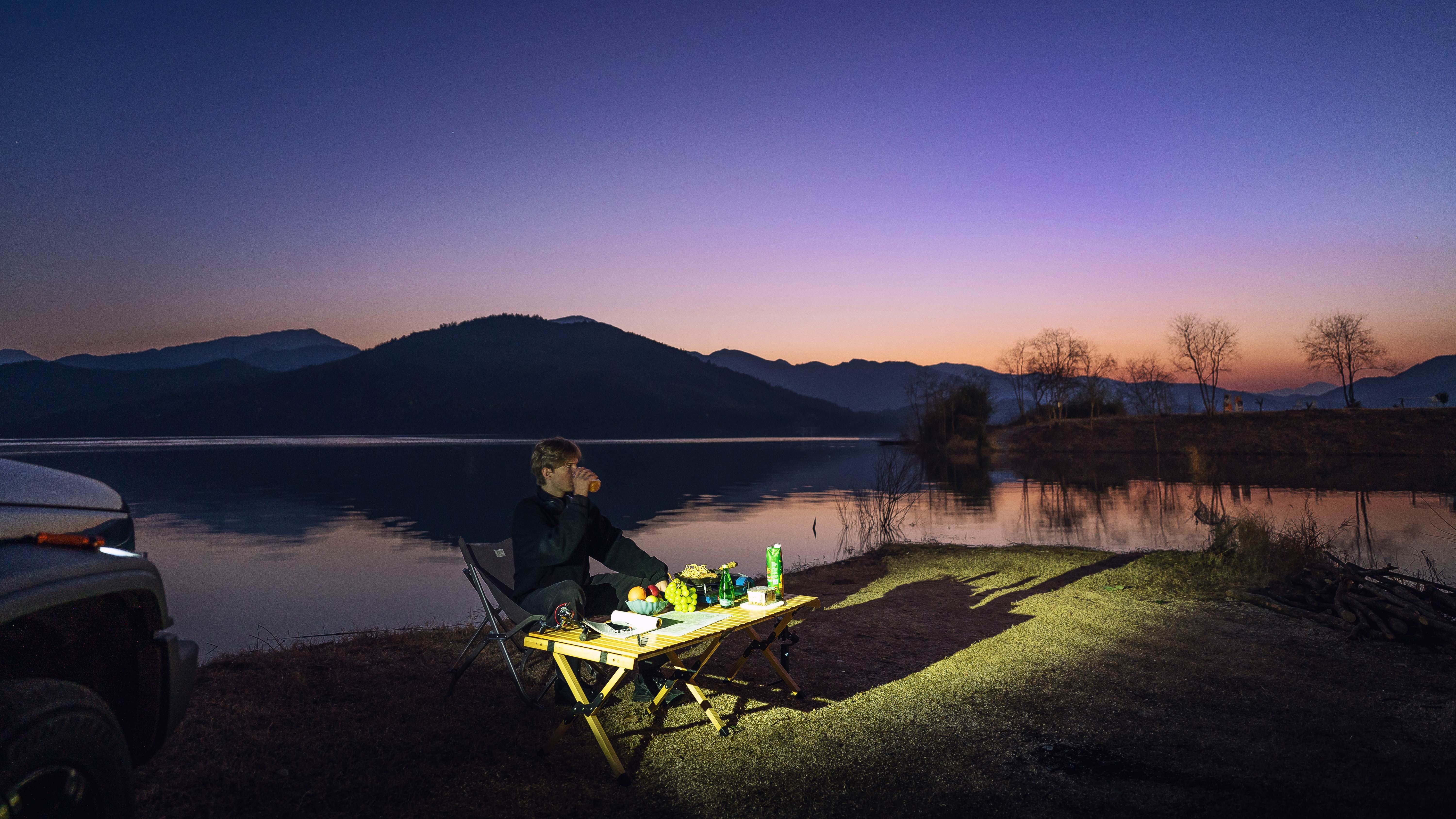Man enjoying a peaceful lakeside picnic at twilight