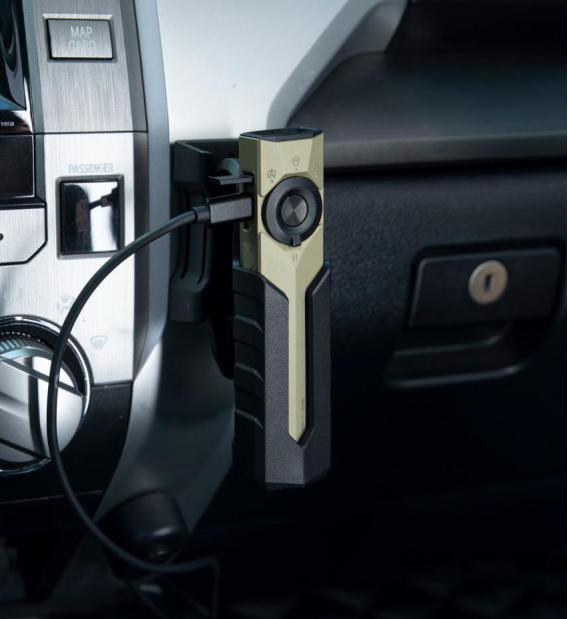 Olight ArkPro compact flat EDC flashlight securely resting on a car dashboard mount.