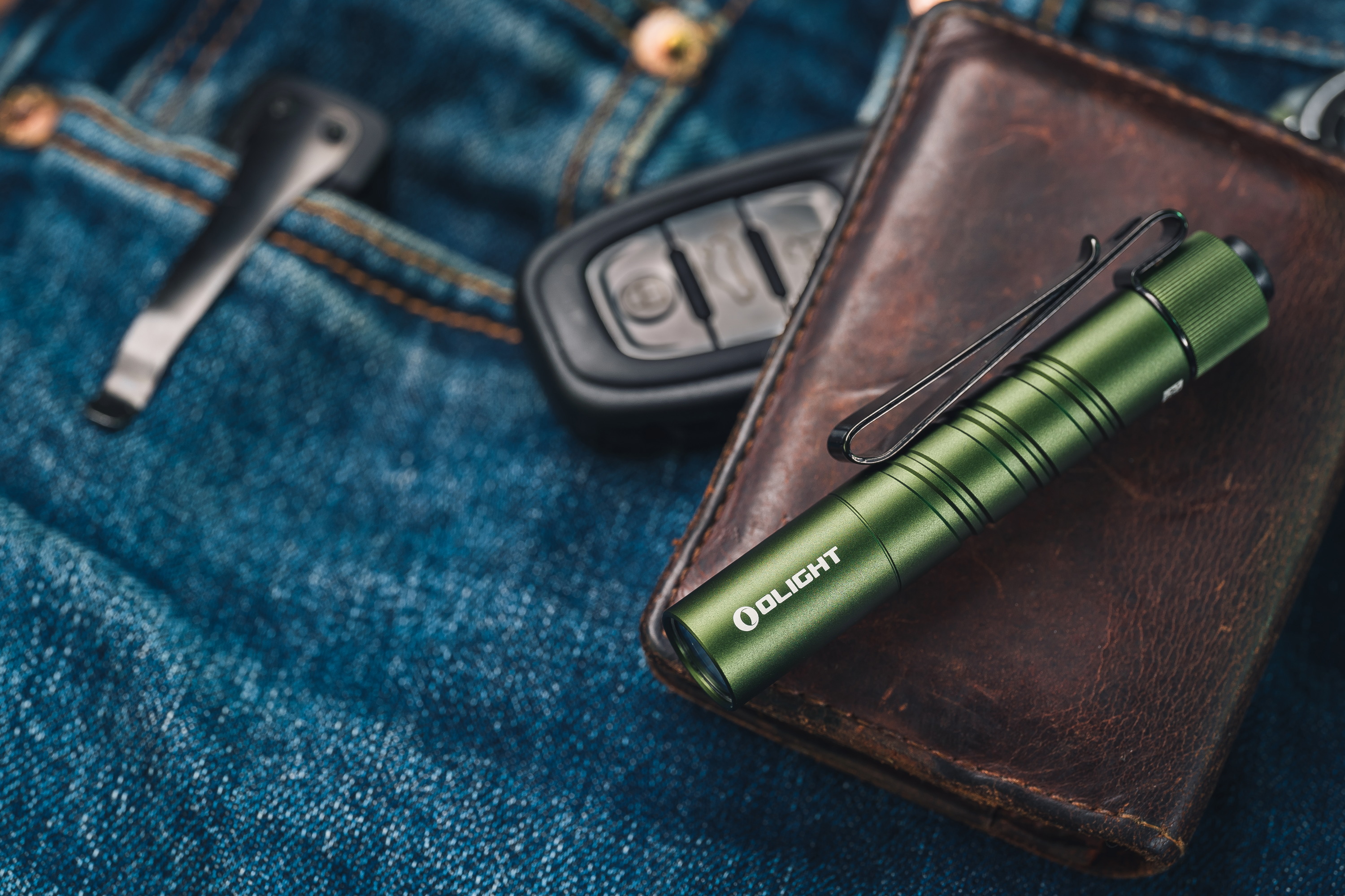 Lampe de poche EDC Olight i3T 2 EOS verte sur cuir et jean