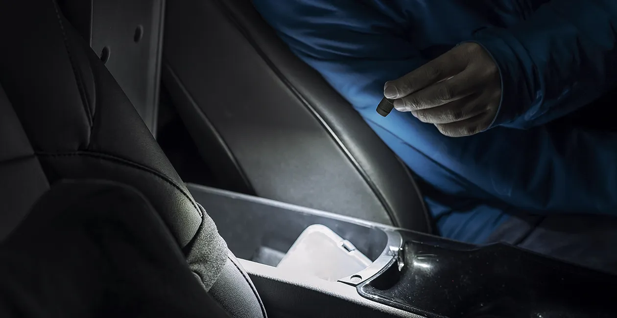 Mini linterna LED port&aacute;til iluminando la consola central y el compartimento de almacenamiento en el interior de un coche en la oscuridad.