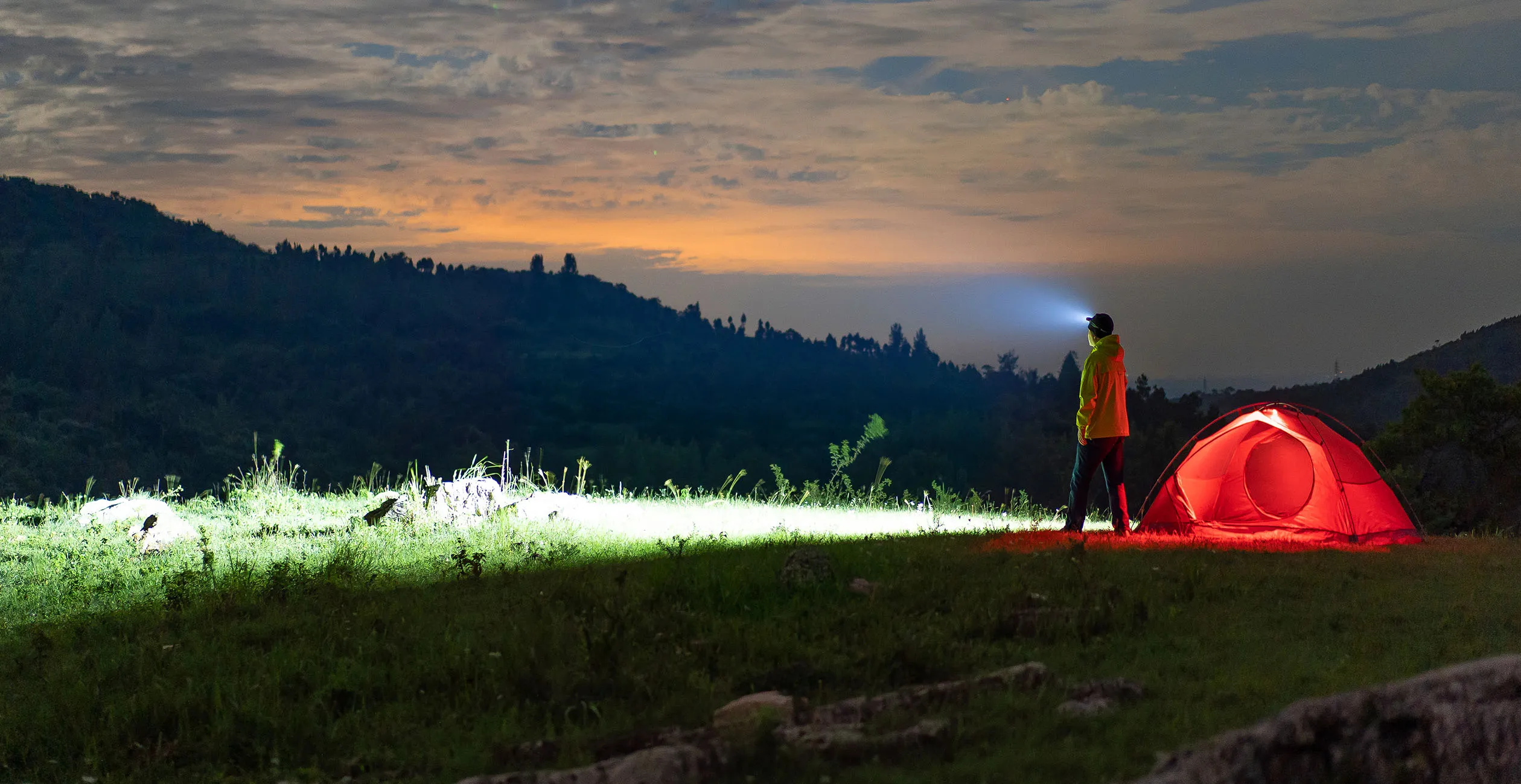Man wearing LED head torch outside illuminated tent