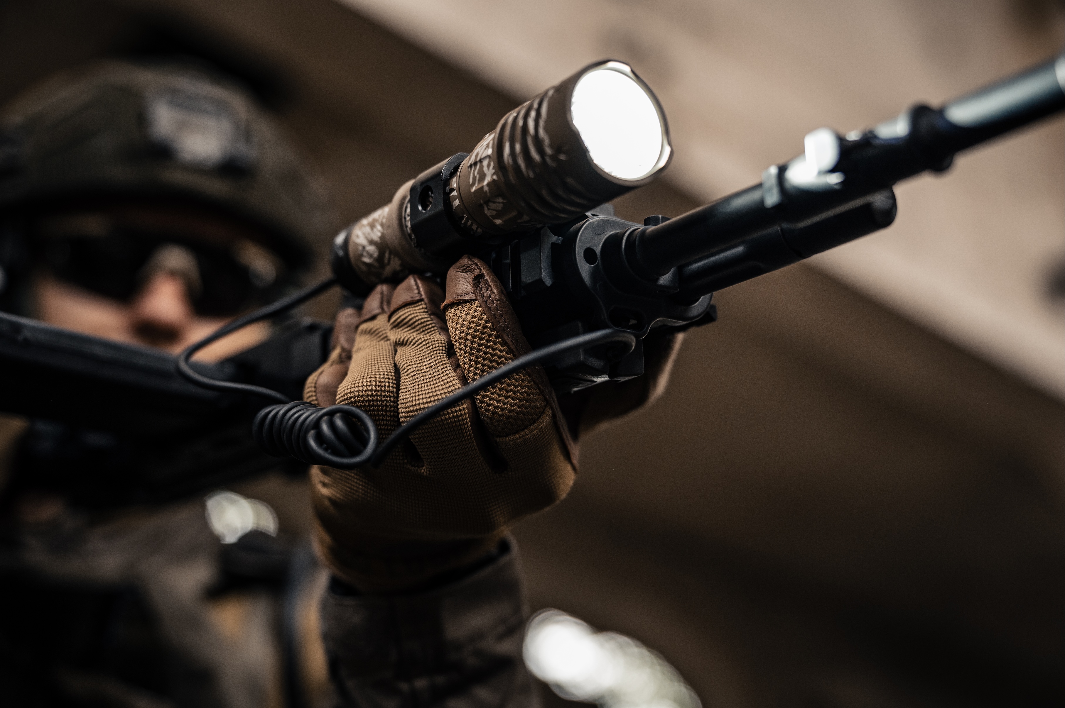 Person mit taktischem Gewehr, heller Taschenlampe und Handschuhen.