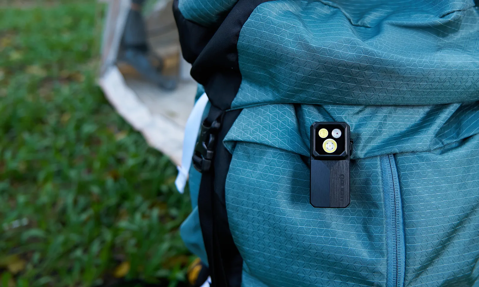 Lampe torche compacte Olight Oclip 2 Ultra fix&eacute;e sur un sac &agrave; dos de randonn&eacute;e bleu en plein air