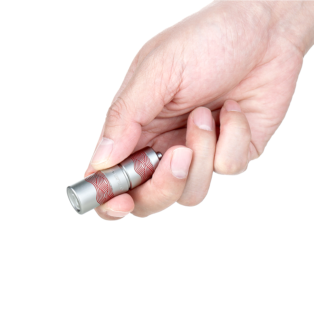 手に持ったOlightミニ懐中電灯。シルバーのボディに赤い波模様が特徴の小型キーライト。