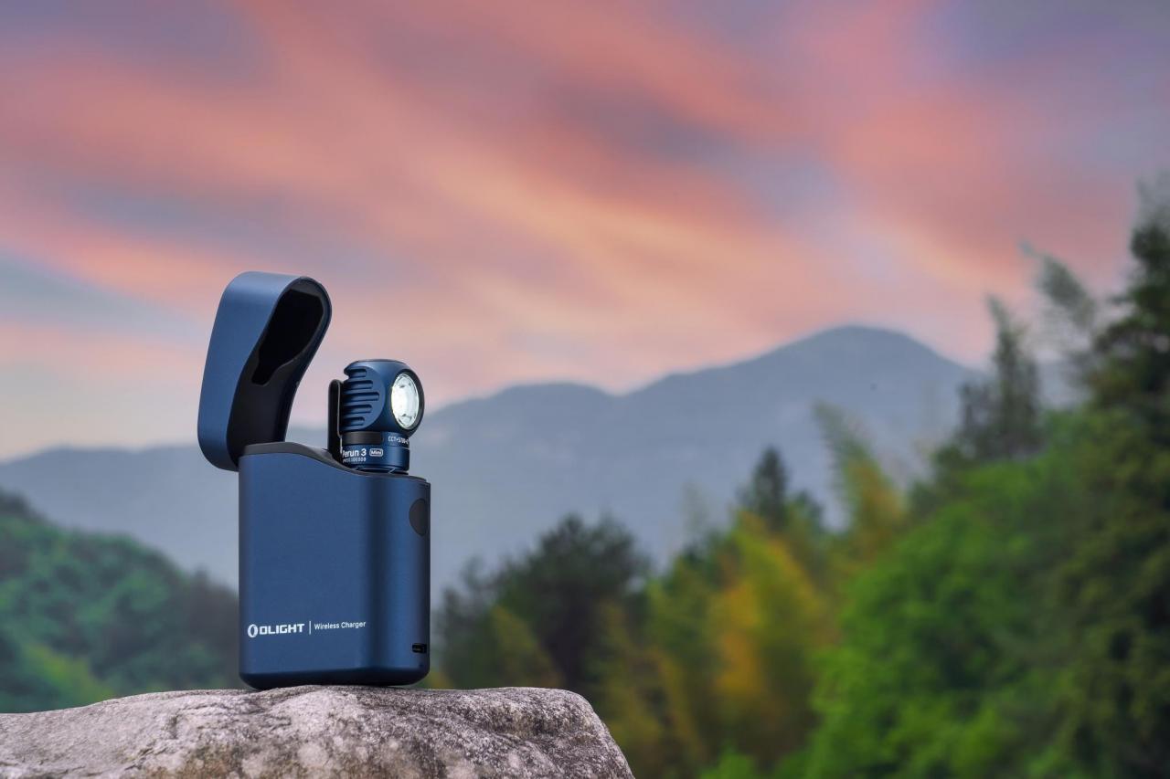 Olight Perun 3 Mini flashlight and wireless charging case resting on a rock