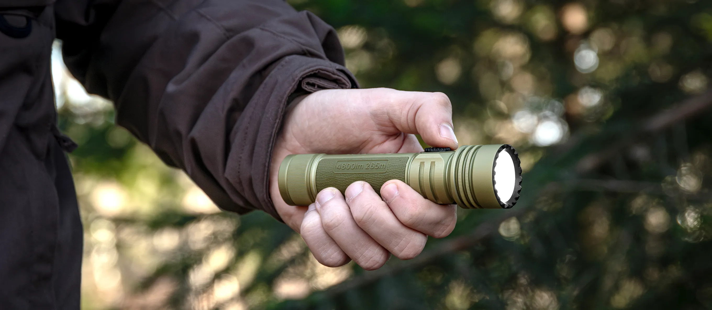 Lampe torche tactique LED puissante couleur vert olive tenue en main en pleine for&ecirc;t pour randonn&eacute;e et survie nocturne