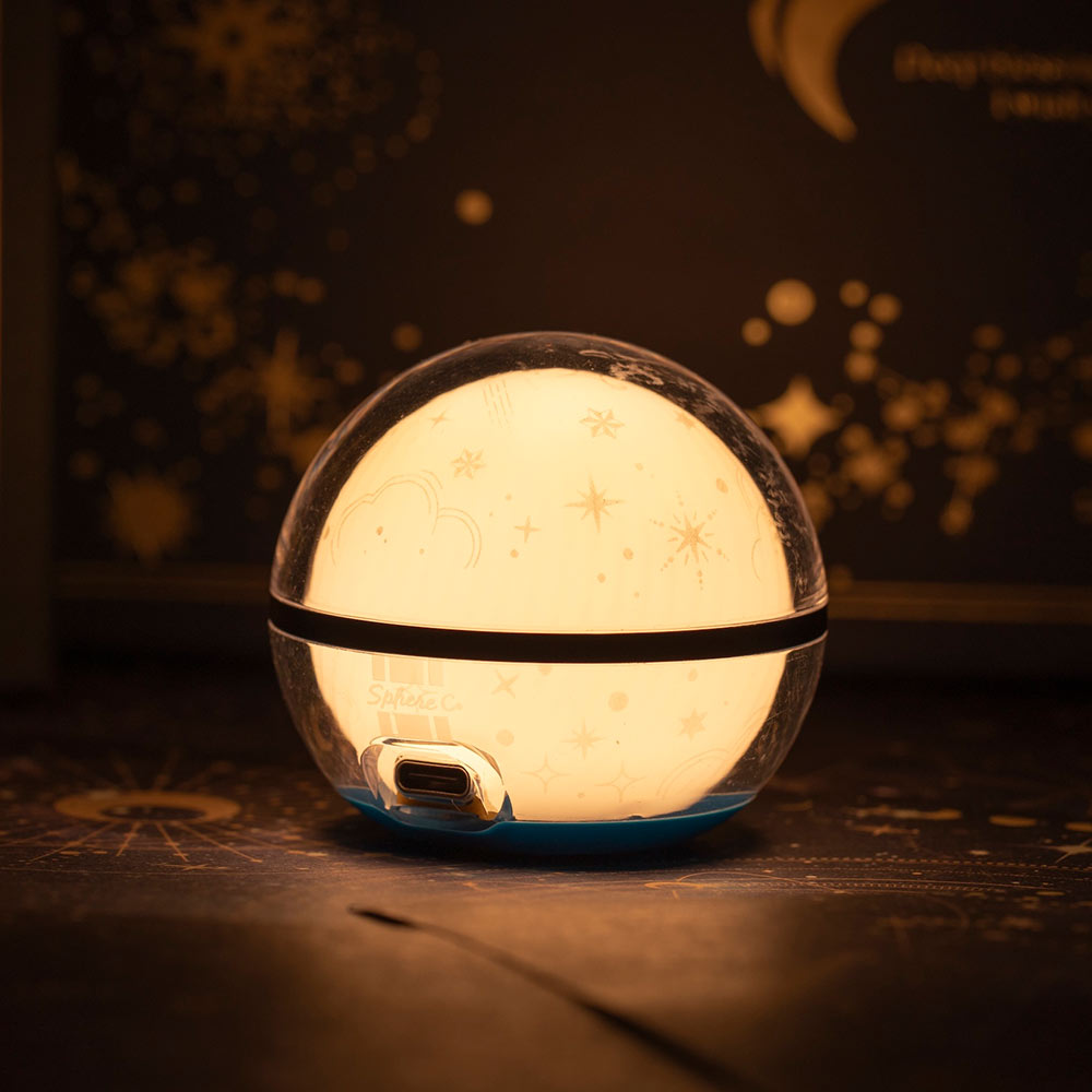 Veilleuse bébé LED en forme de boule lumineuse avec motifs étoiles et nuages, lumière chaude tamisée et port USB de recharge, idéale pour la décoration de chambre d'enfant et aide au sommeil.