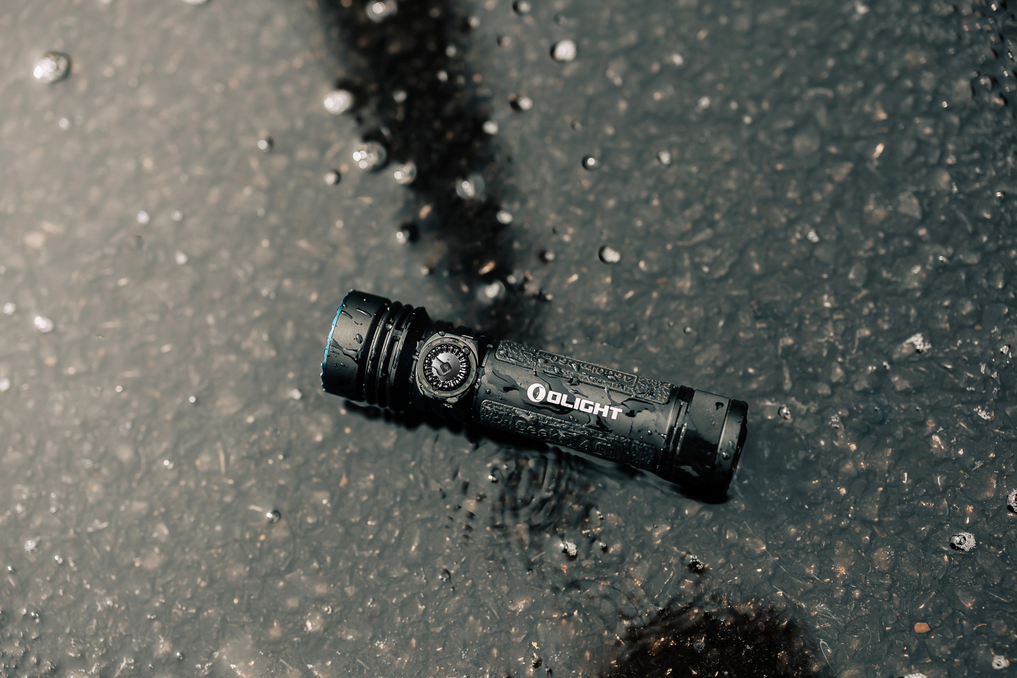 Rugged Olight waterproof tactical flashlight on wet asphalt