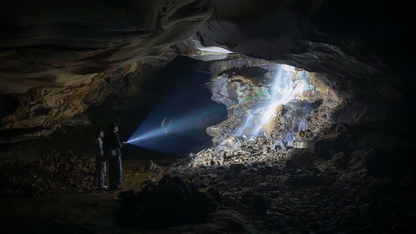 Exploring a dark cavern using a powerful Olight flashlight.