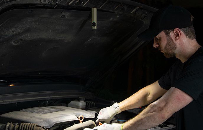 Magnetic LED work light attached to a car hood for engine inspection