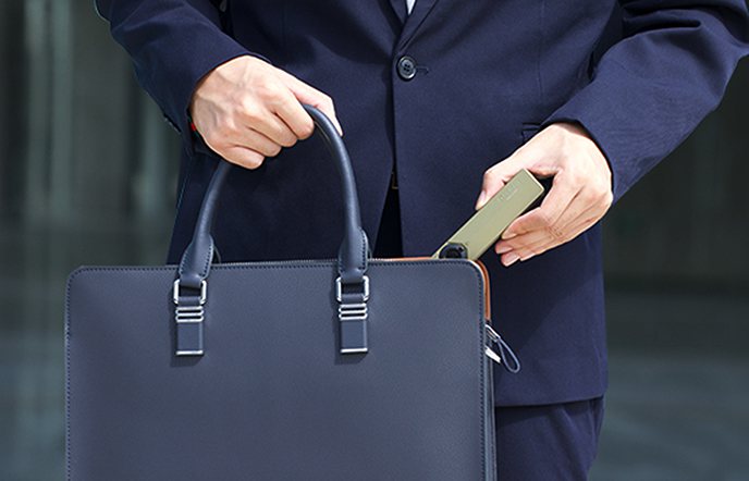 Professional businessman putting a slim, portable power bank into a navy leather briefcase